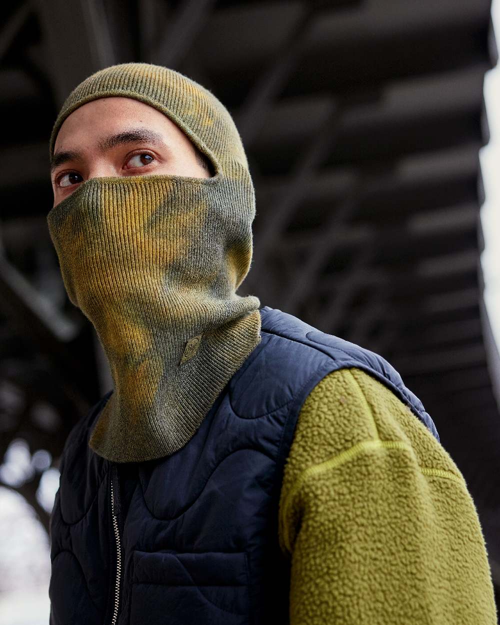 Khaki Coloured Buff Nilan Knitted Balaclava on blurry background #colour_khaki