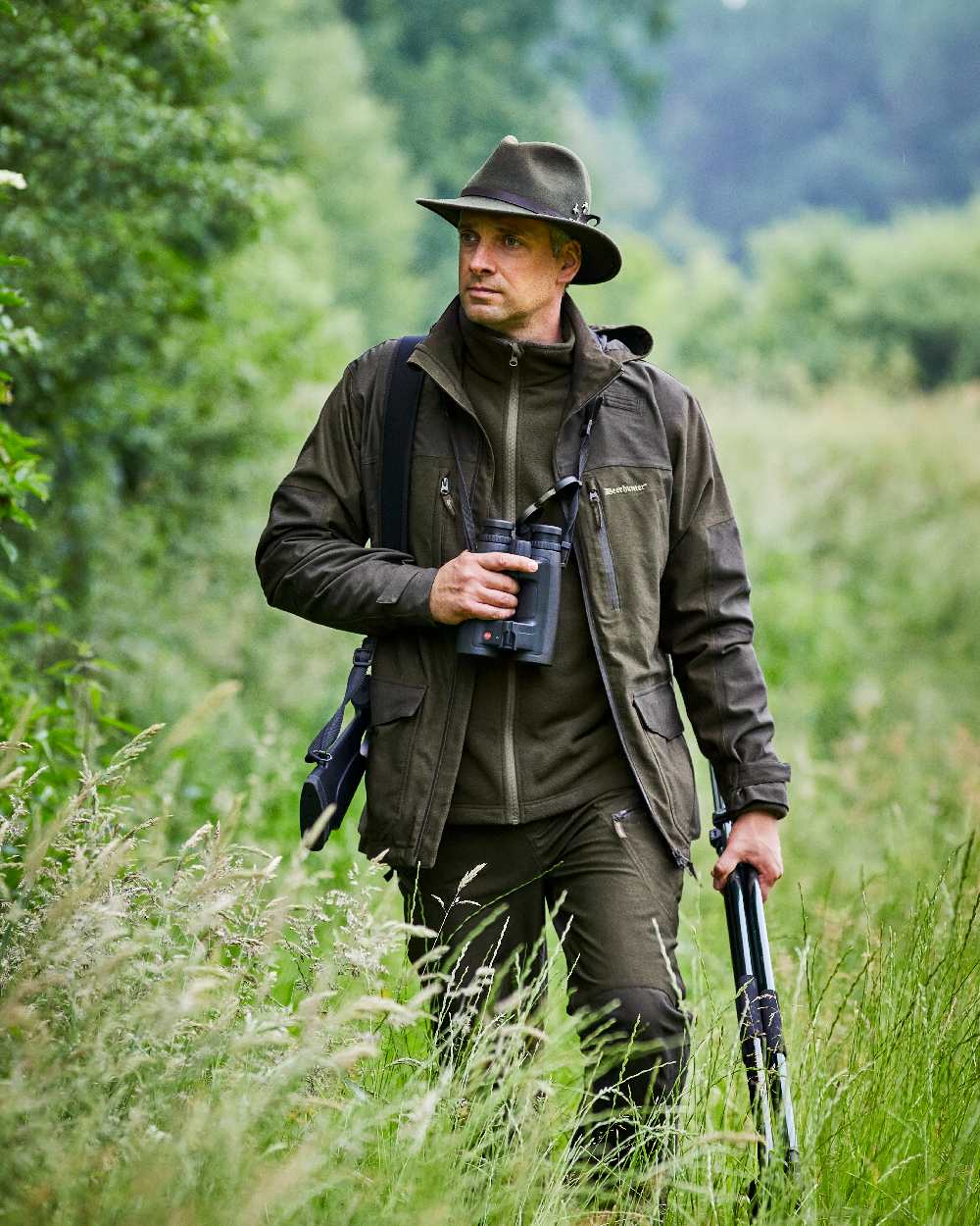 Olive Green Melange Coloured Deerhunter Chasse Jacket on forest background #colour_olive-green-melange