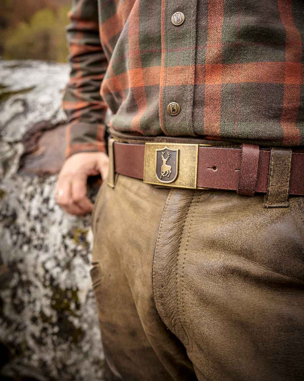 Cognac Brown coloured Deerhunter Deer Buckle Leather Belt on blurry background #colour_cognac-brown