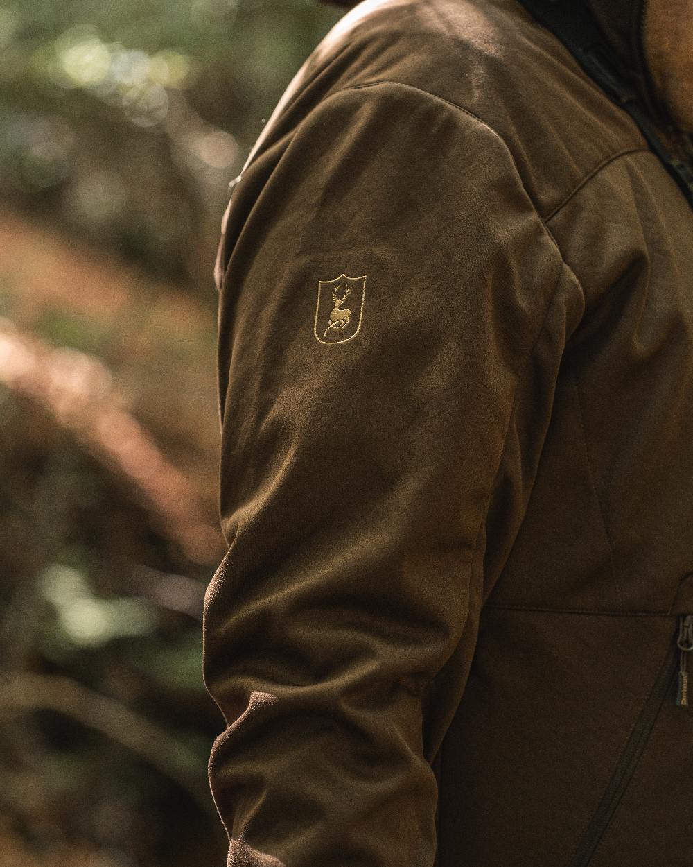 Art Green coloured Deerhunter Excape Softshell Jacket on blurry background #colour_art-green