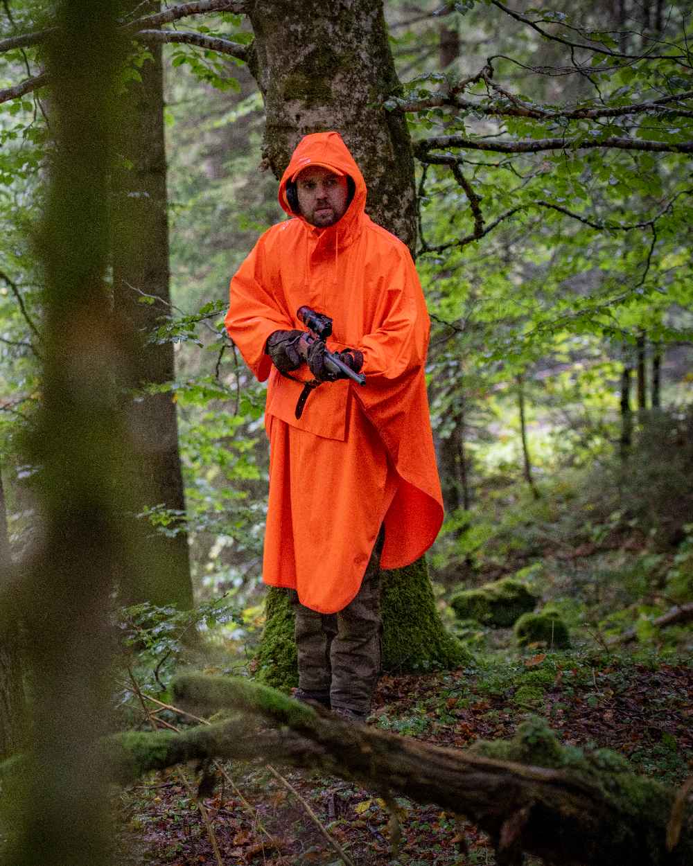 Orange coloured Deerhunter Hurricane Rain Poncho on forest background #colour_orange