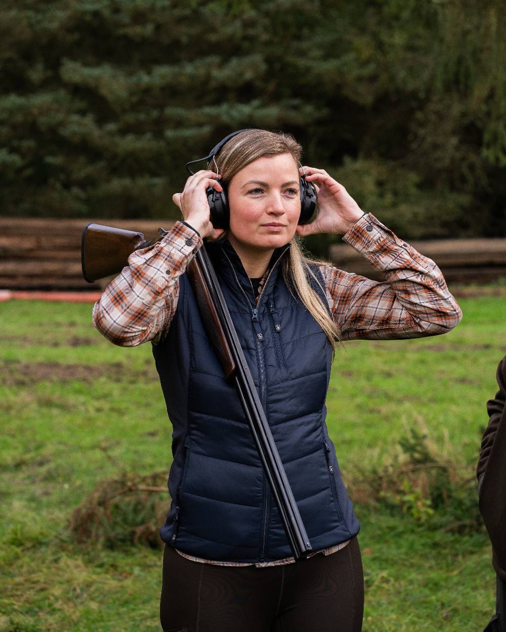 Dark Blue Coloured Deerhunter Lady Heat Padded Waistcoat on forest background #colour_dark-blue
