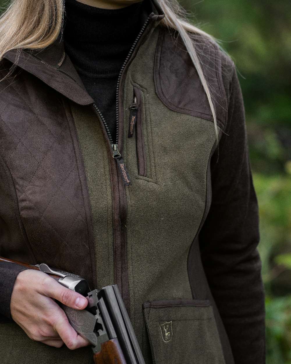 Graphite Green coloured Deerhunter Lady Pam Shooting Waistcoat on blurry background #colour_graphite-green