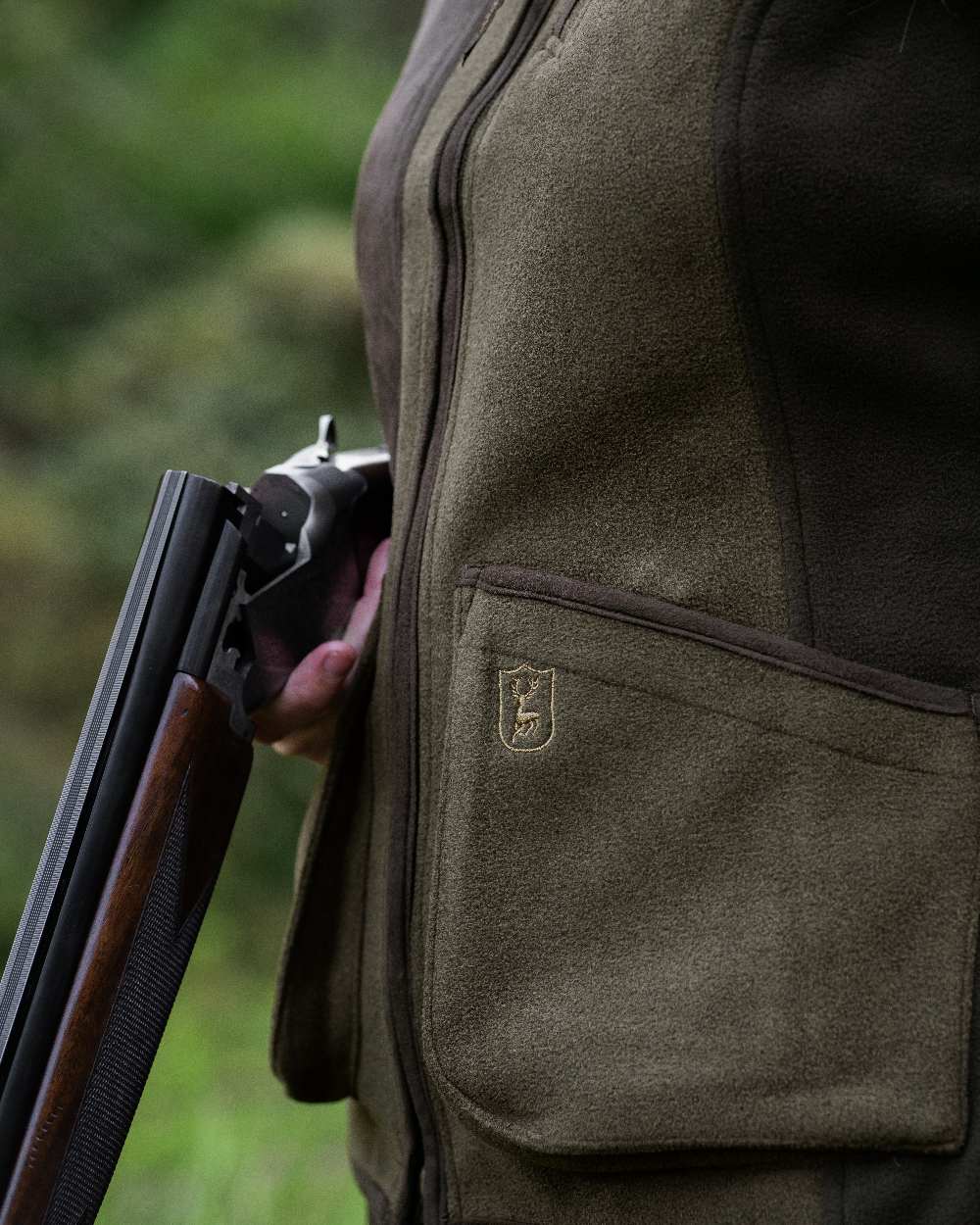 Graphite Green coloured Deerhunter Lady Pam Shooting Waistcoat on blurry background #colour_graphite-green