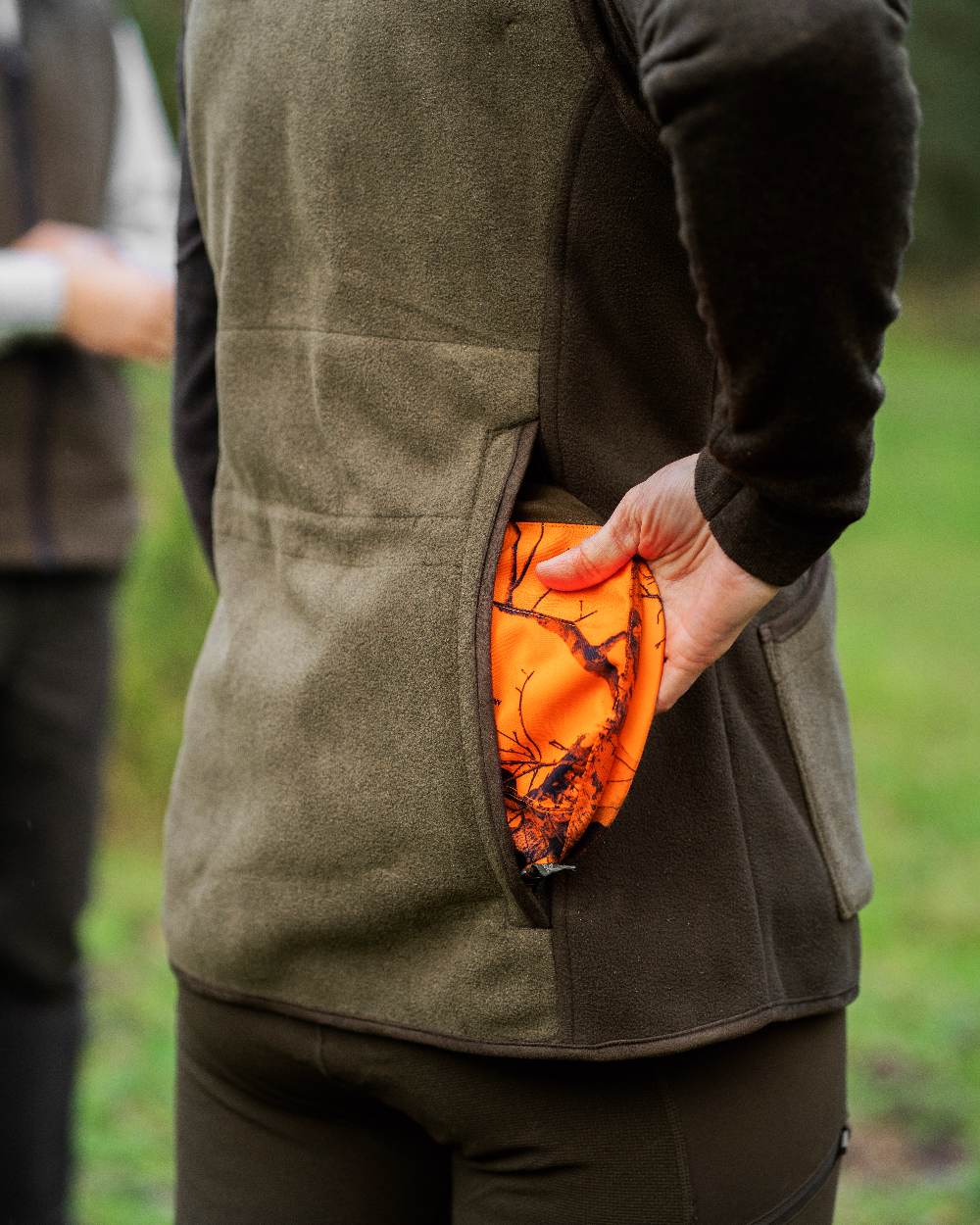 Graphite Green coloured Deerhunter Lady Pam Shooting Waistcoat on blurry background #colour_graphite-green