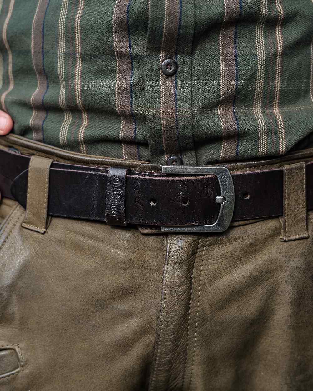 Dark Brown coloured Deerhunter Leather Belt on blurry background #colour_dark-brown