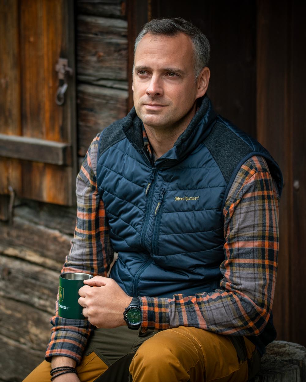 Dark Blue Coloured Deerhunter Moor Padded Waistcoat with Knit on house background #colour_dark-blue
