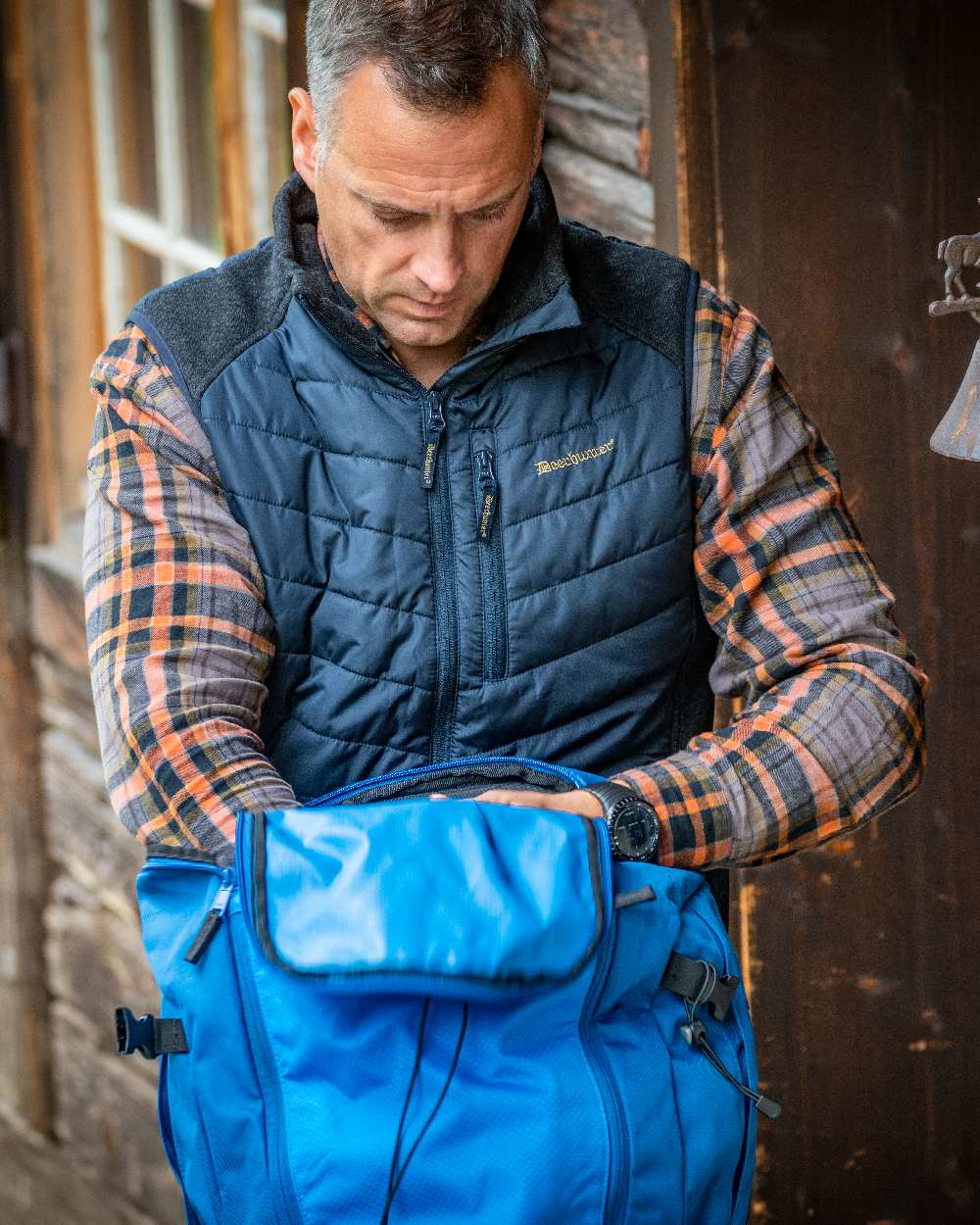 Dark Blue Coloured Deerhunter Moor Padded Waistcoat with Knit on house background #colour_dark-blue
