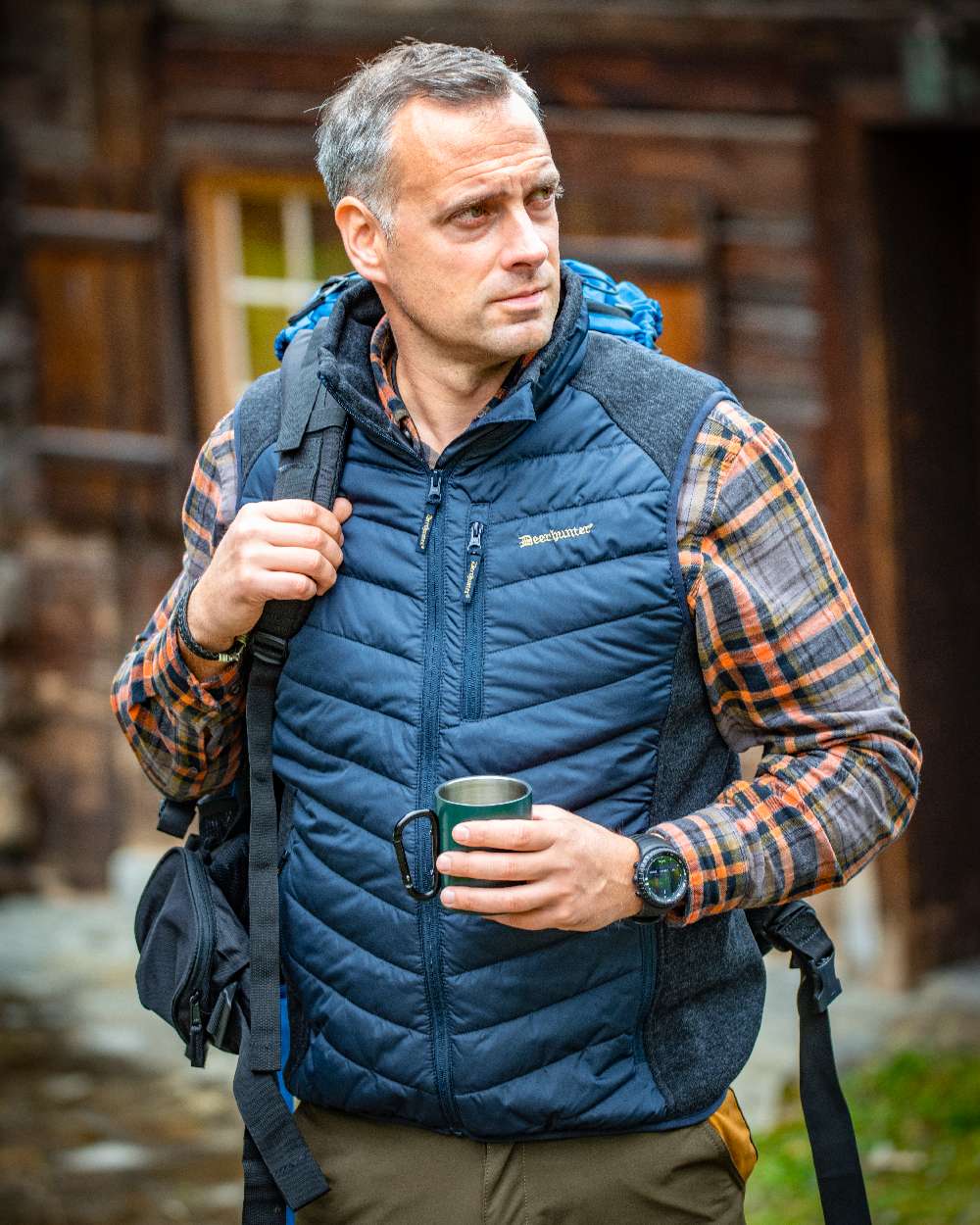Dark Blue Coloured Deerhunter Moor Padded Waistcoat with Knit on blurry background #colour_dark-blue