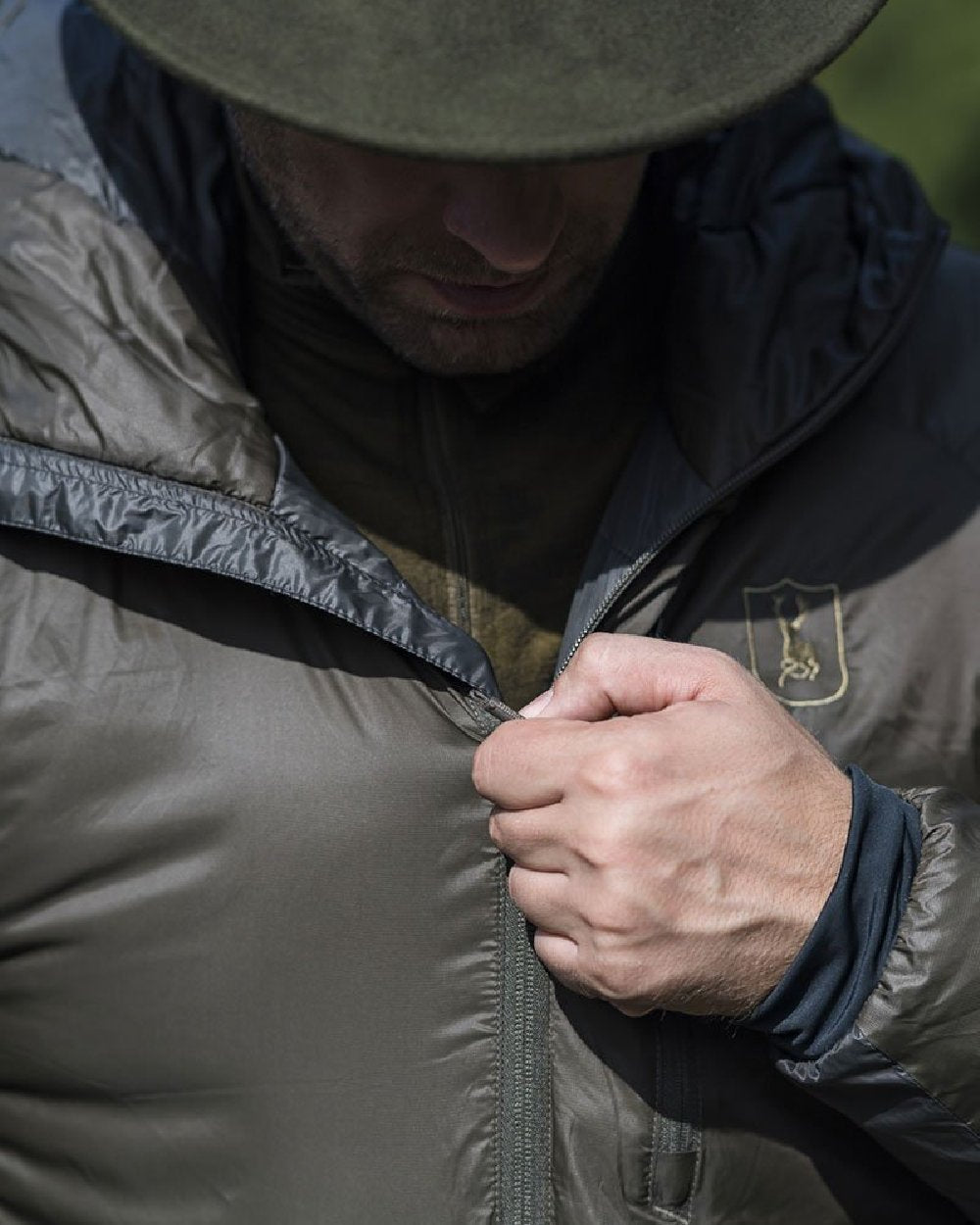 Deep Green Art Green coloured Deerhunter Packable Jacket on blurry background #colour_deep-green-art-green