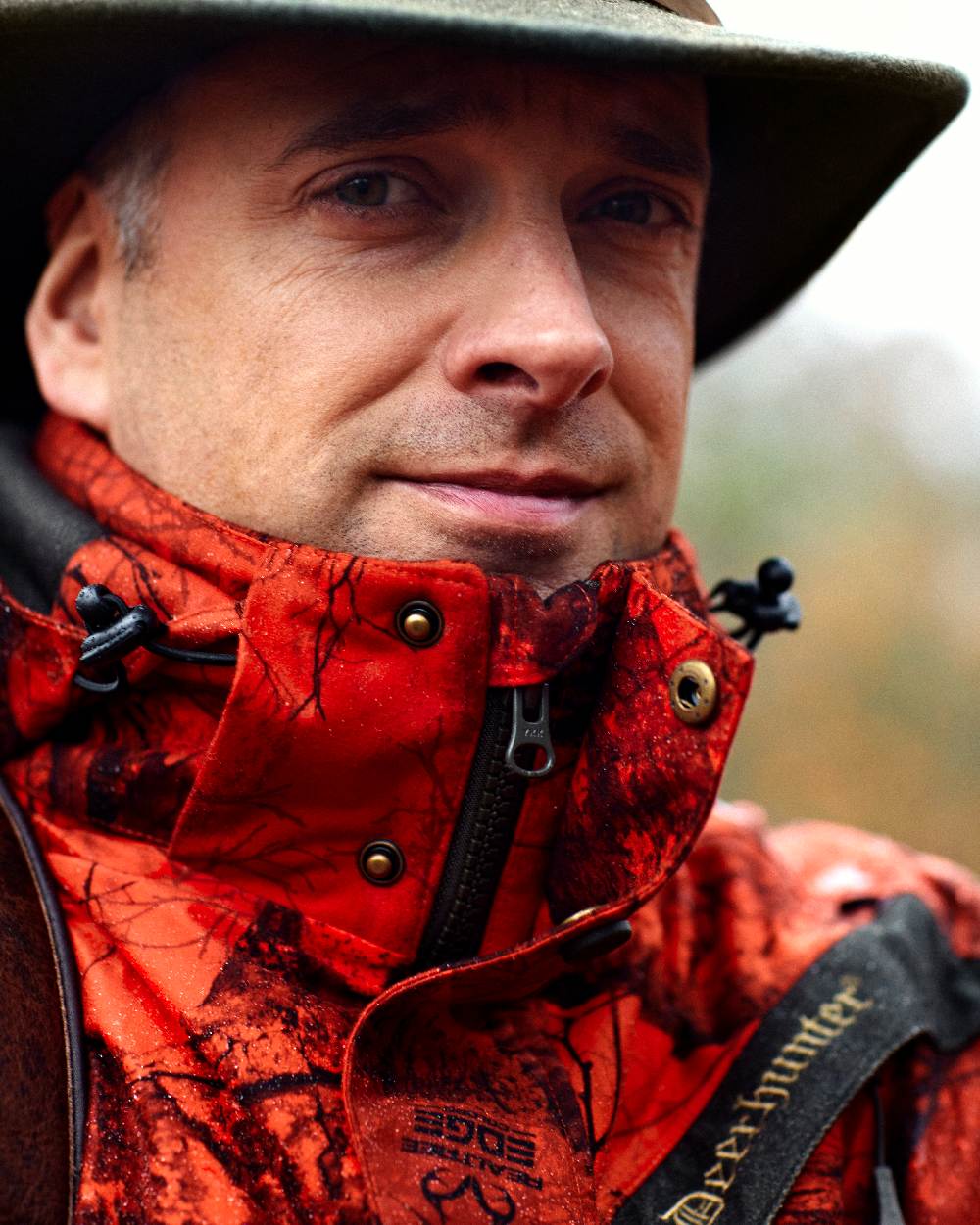 Realtree Edge Red coloured Deerhunter Ram Arctic Jacket on blurry background #colour_realtree-edge-red