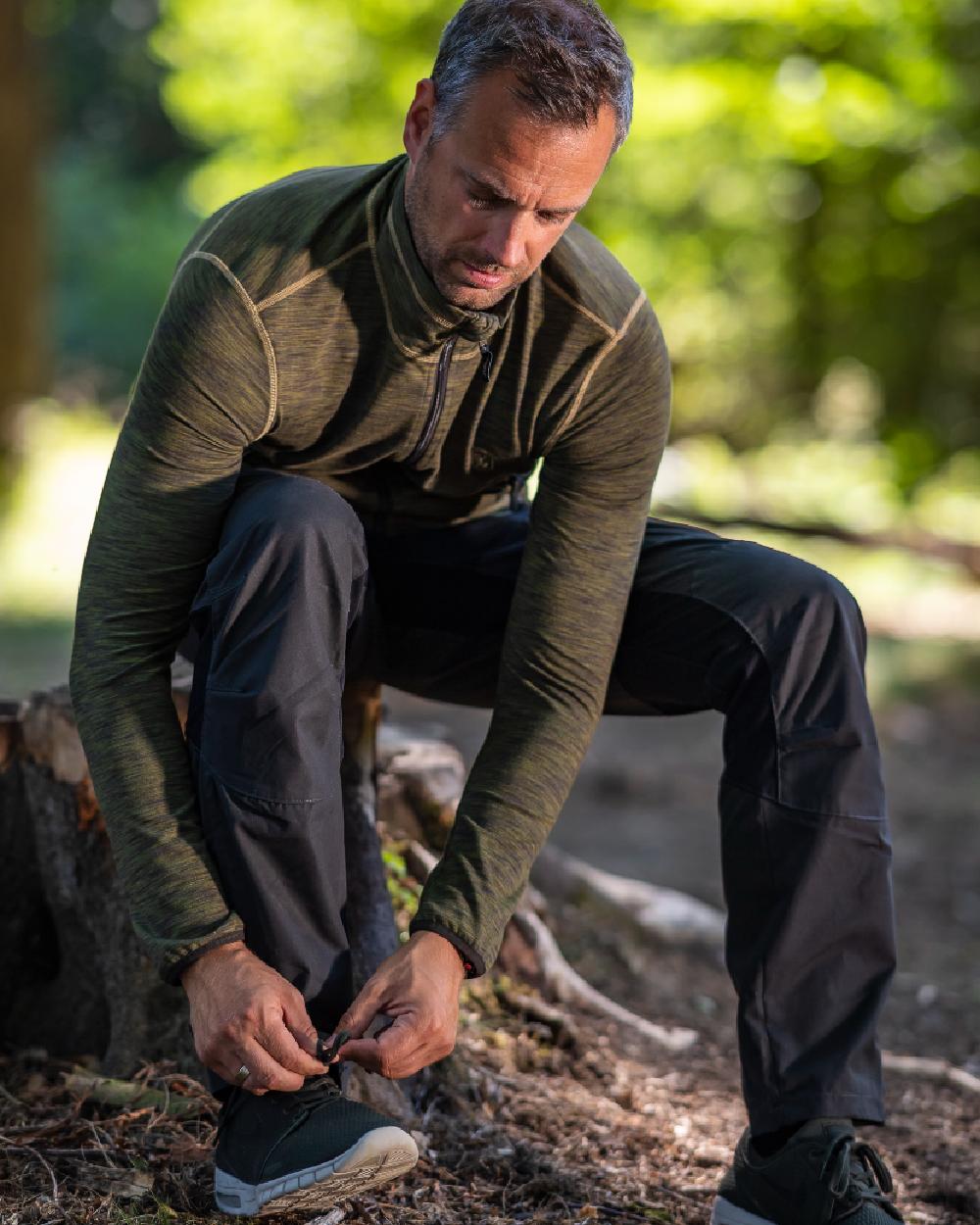 Black coloured Deerhunter Strike Full Stretch Trousers on forest background #colour_black