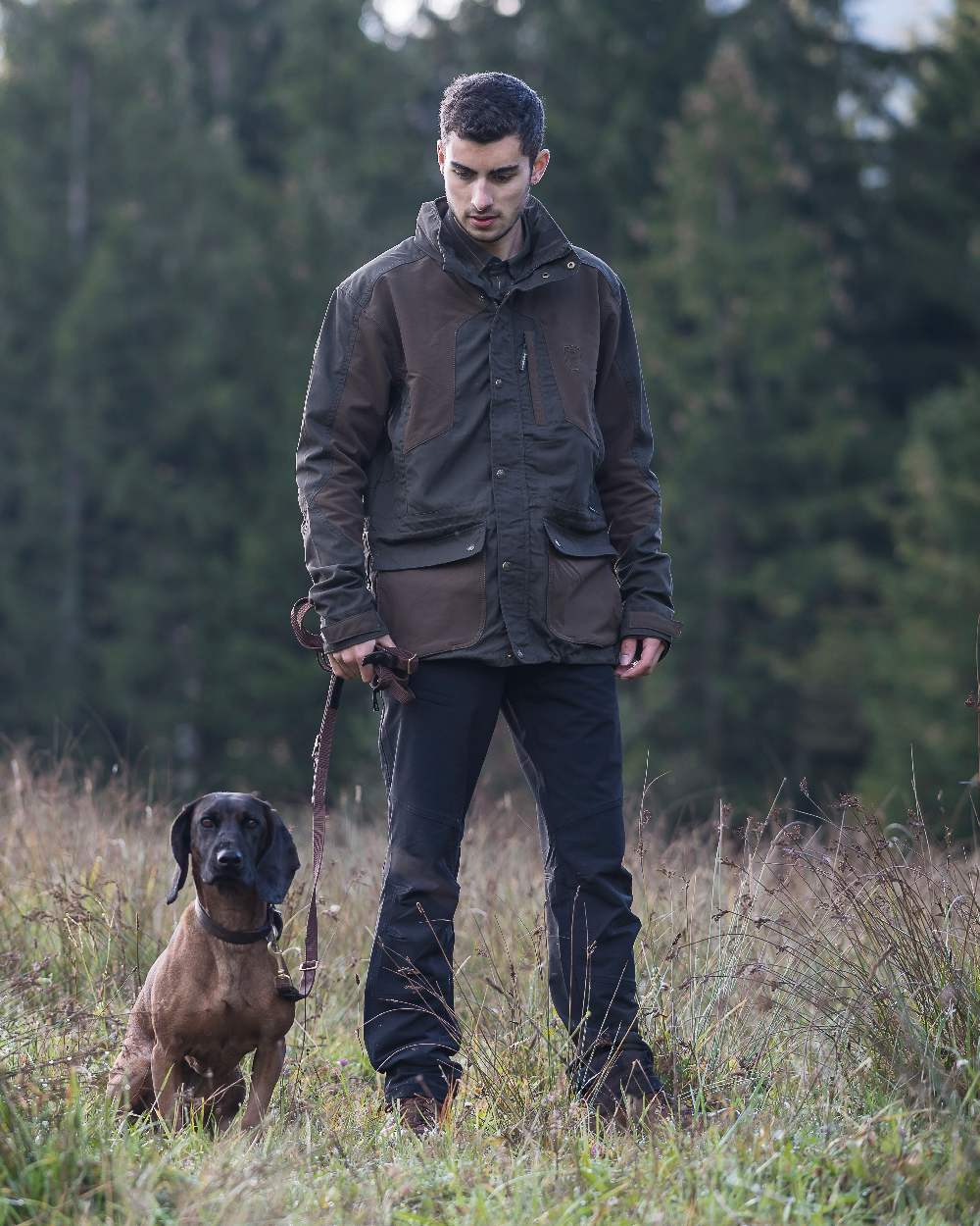 Black coloured Deerhunter Strike Full Stretch Trousers on forest background #colour_black