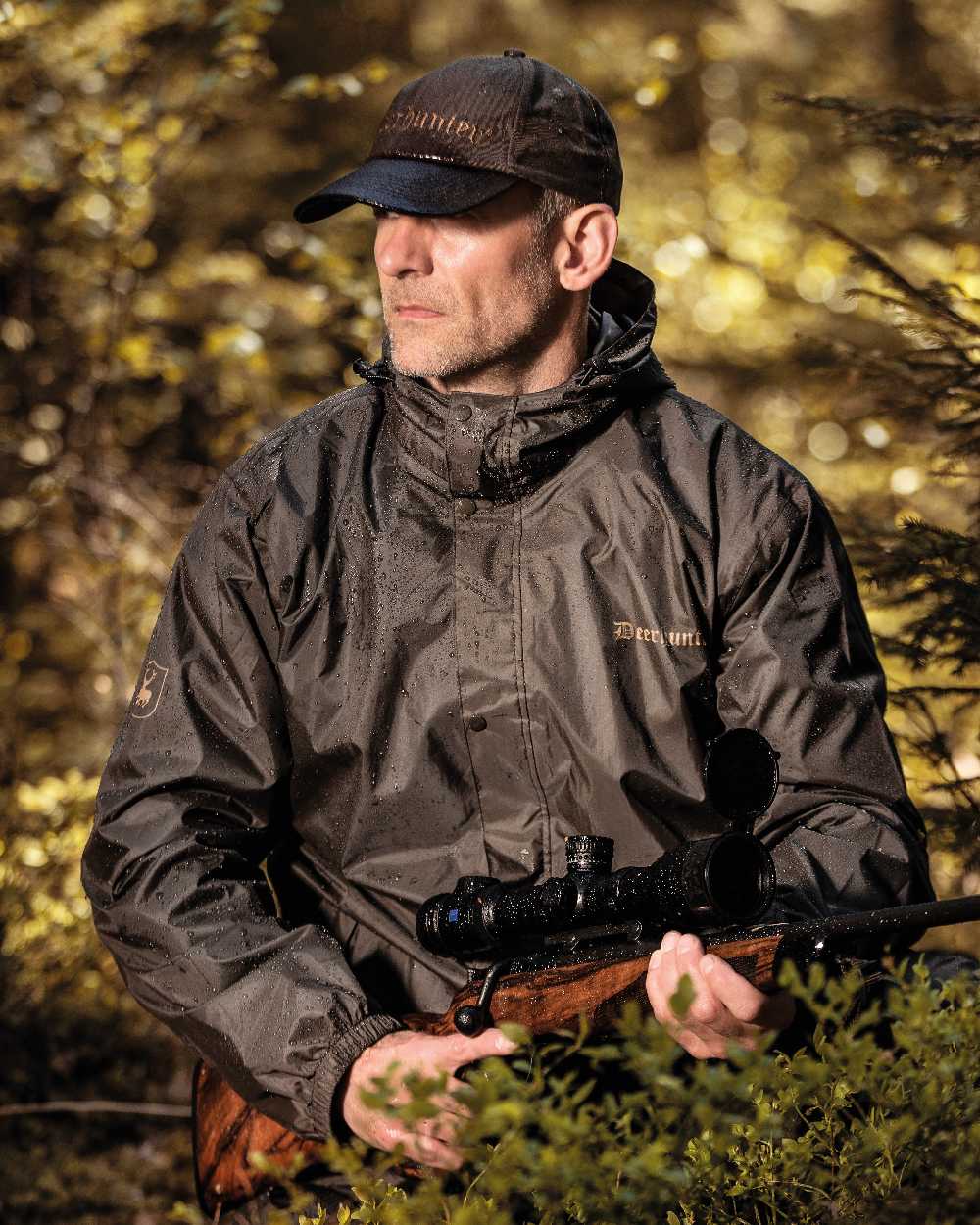 Timber coloured Deerhunter Survivor Packable Rain Jacket on forest background #colour_timber