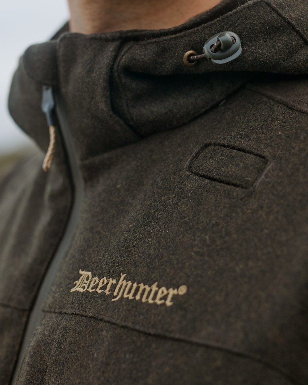 Loden Wood Coloured Deerhunter Tatra Jacket On A Forest Background #colour_loden-wood