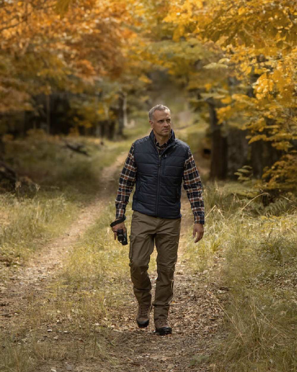 Hickory coloured Deerhunter Traveler Trousers on forest background #colour_hickory