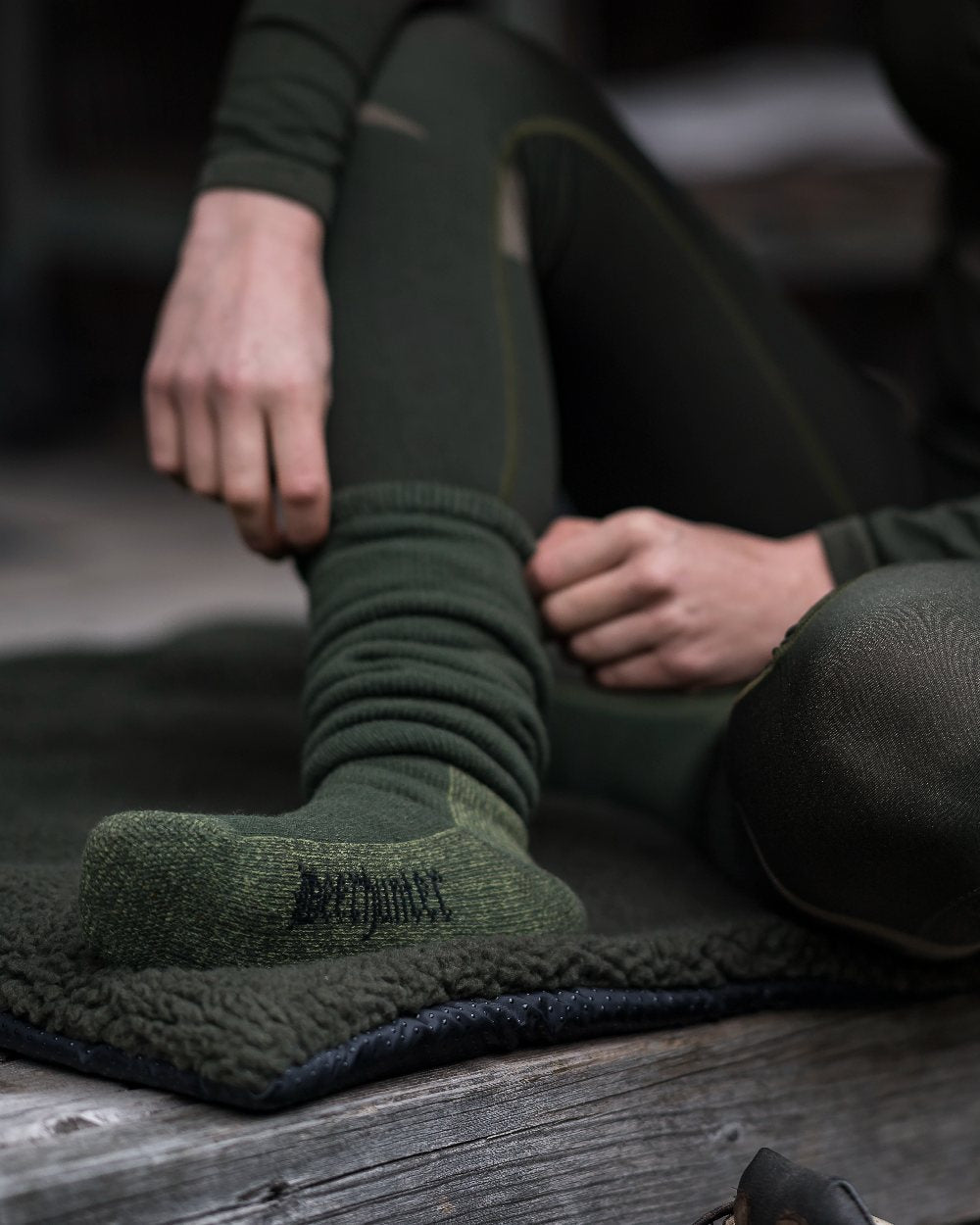 Grape Leaf coloured Deerhunter Wool Socks Deluxe Long on bench background #colour_grape-leaf