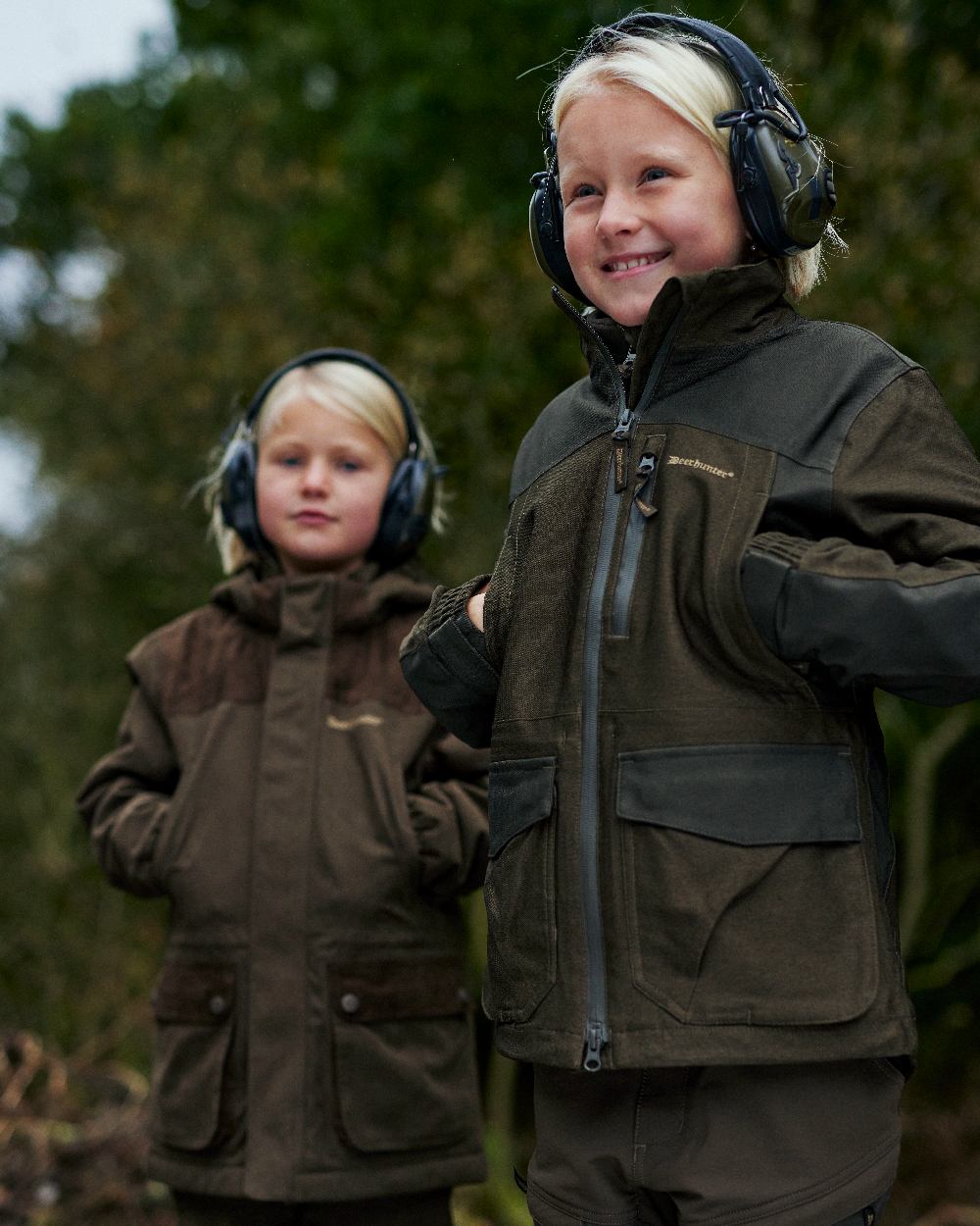 Olive Night Melange coloured Deerhunter Youth Chasse Jacket on forest background #colour_olive-night-melange