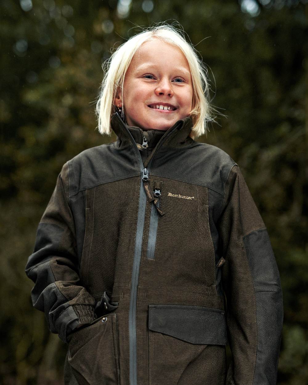 Olive Night Melange coloured Deerhunter Youth Chasse Jacket on forest background #colour_olive-night-melange