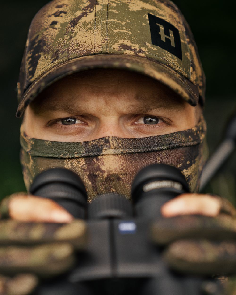 AXIS Forest Coloured Harkila Deer Stalker Camo Mesh Face Cover on blurry background #colour_axis-forest