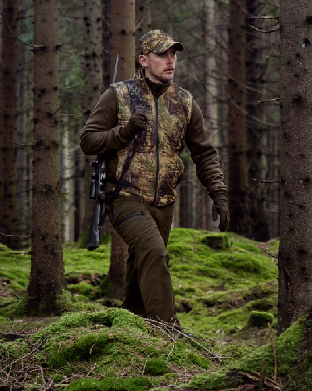 Willow Green AXIS Forest Coloured Harkila Deer Stalker Camo Reversible Packable Waistcoat on forest background #colour_willow-green-axis-forest