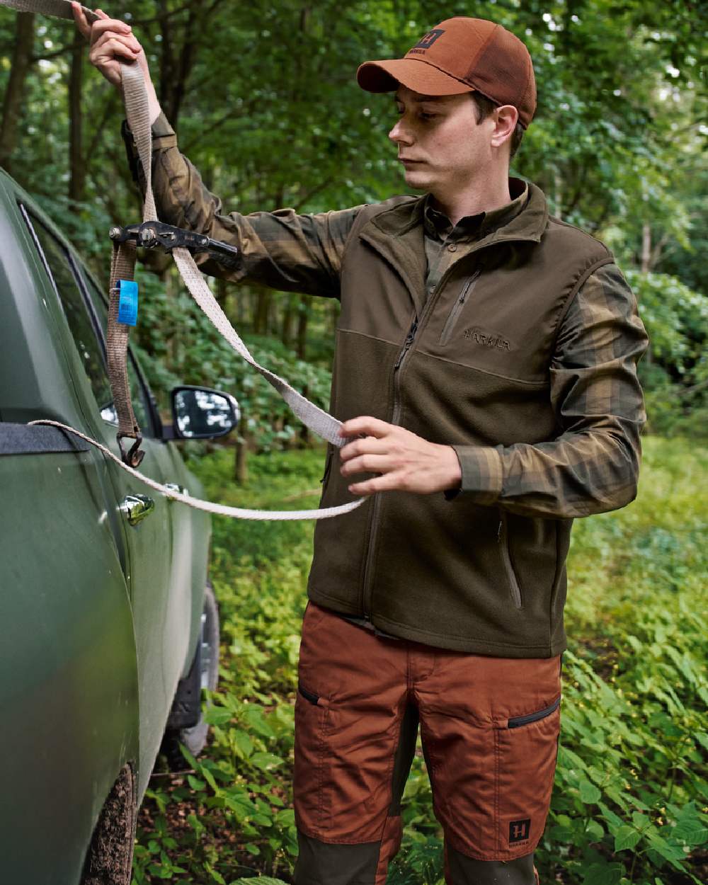 Hunting Green Willow Green Coloured Harkila Fjell Fleece Waistcoat on forest background #colour_hunting-green-willow-green