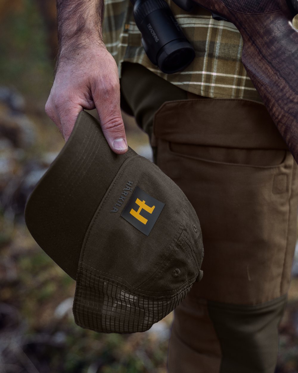 Willow Green Coloured Harkila Instinct Cap on blurry background #colour_willow-green