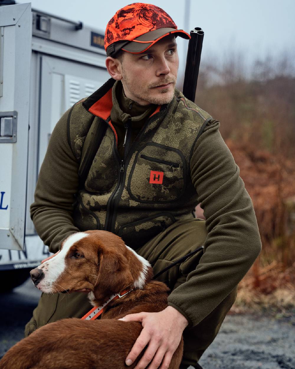 AXIS Limited Edition Orange Coloured Harkila Kamko Pro Edition Reversible Hi-Vis Waistcoat on forest background #colour_axis-limited-edition-orange