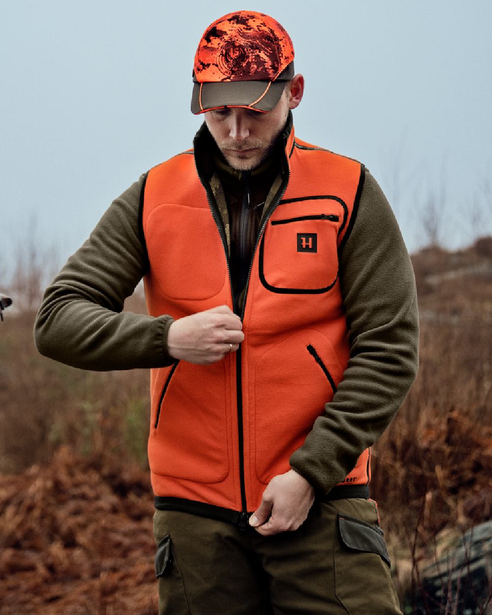 AXIS Limited Edition Orange Coloured Harkila Kamko Pro Edition Reversible Hi-Vis Waistcoat on forest background #colour_axis-limited-edition-orange