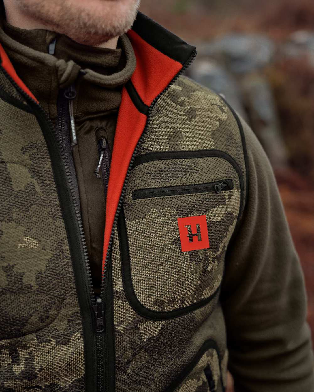 AXIS Limited Edition Orange Coloured Harkila Kamko Pro Edition Reversible Hi-Vis Waistcoat on forest background #colour_axis-limited-edition-orange