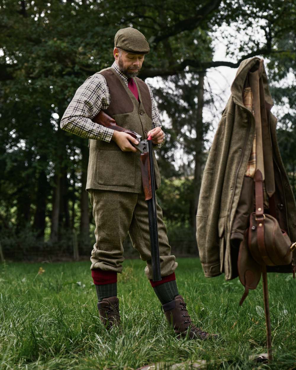 Forest Green Herringbone coloured Harkila Kenmore Shooting Waistcoat on forest background #colour_forest-green-herringbone