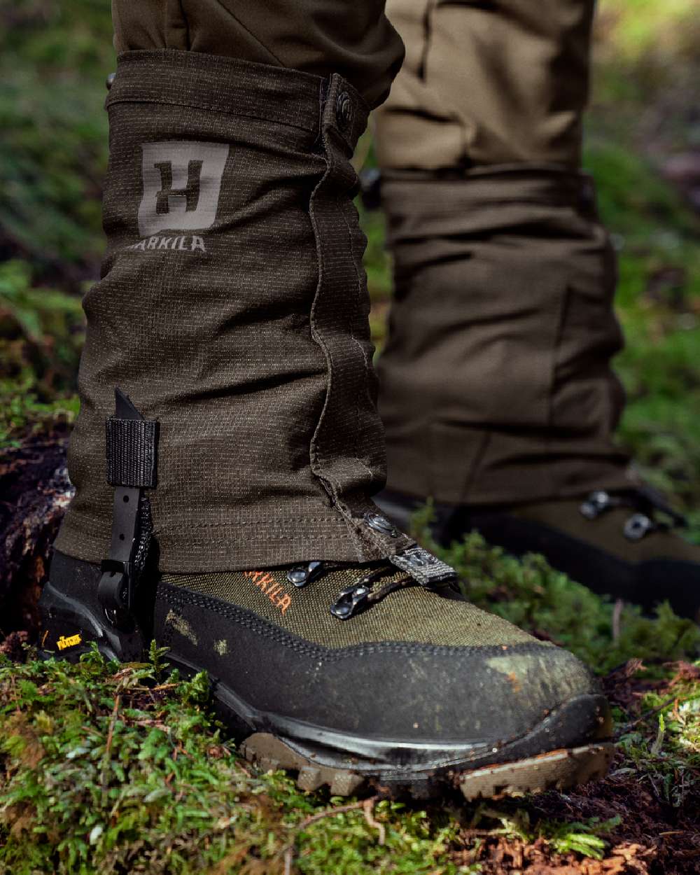 Shadow Brown Coloured Harkila Ledge Gaiters on forest background #colour_shadow-brown