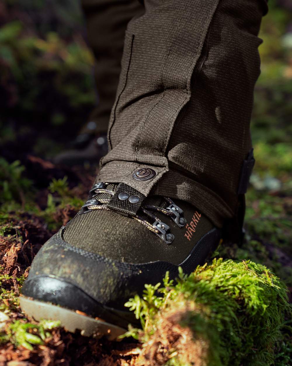Shadow Brown Coloured Harkila Ledge Gaiters on forest background #colour_shadow-brown