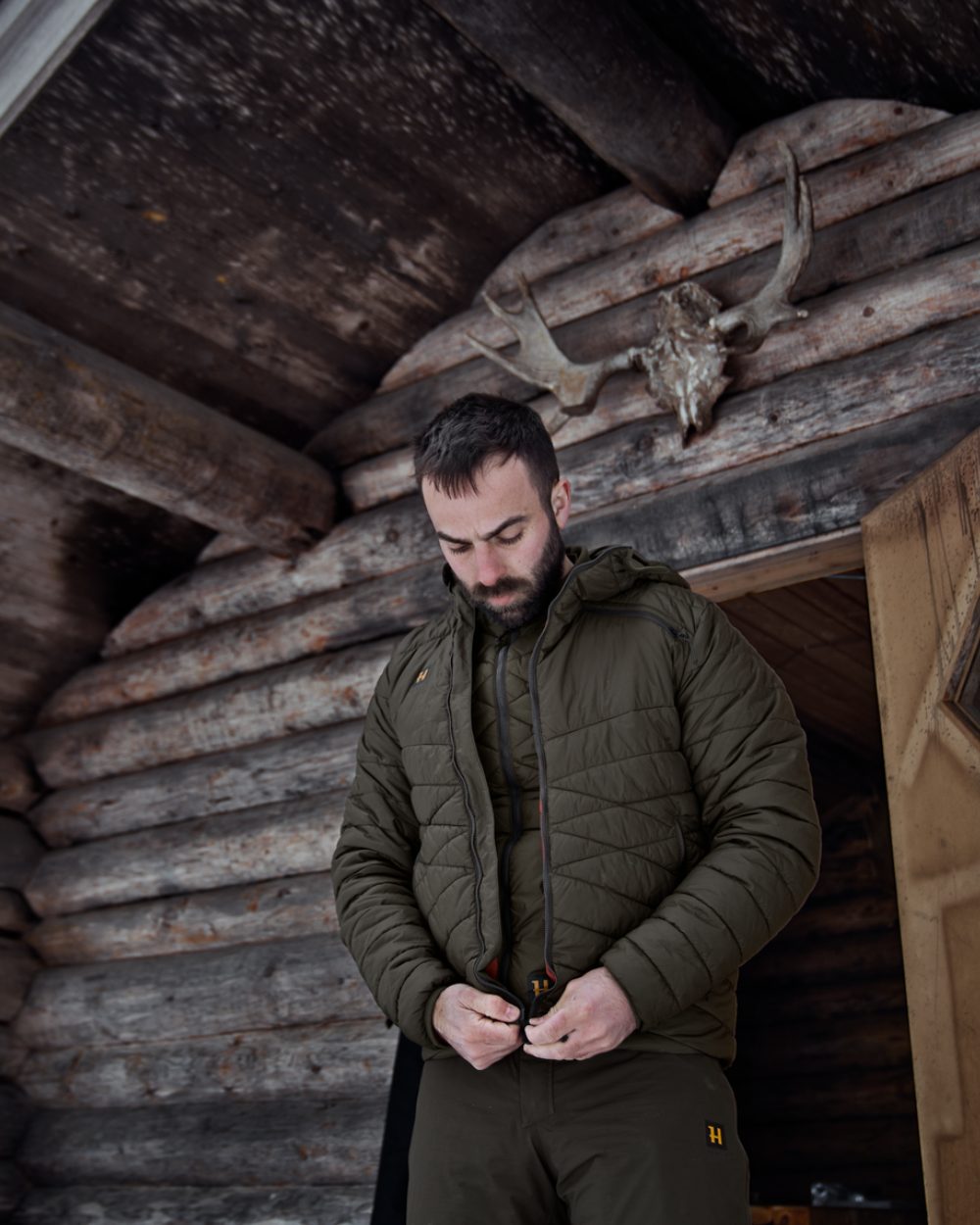 Willow Green Coloured Harkila Logmar Insulated Packable Hooded Jacket on house background #colour_willow-green