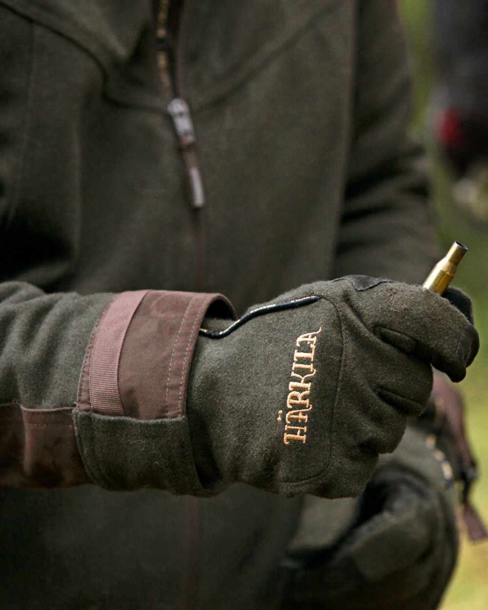 Willow Green Coloured Harkila Metso Active Gloves on blurry background #colour_willow-green