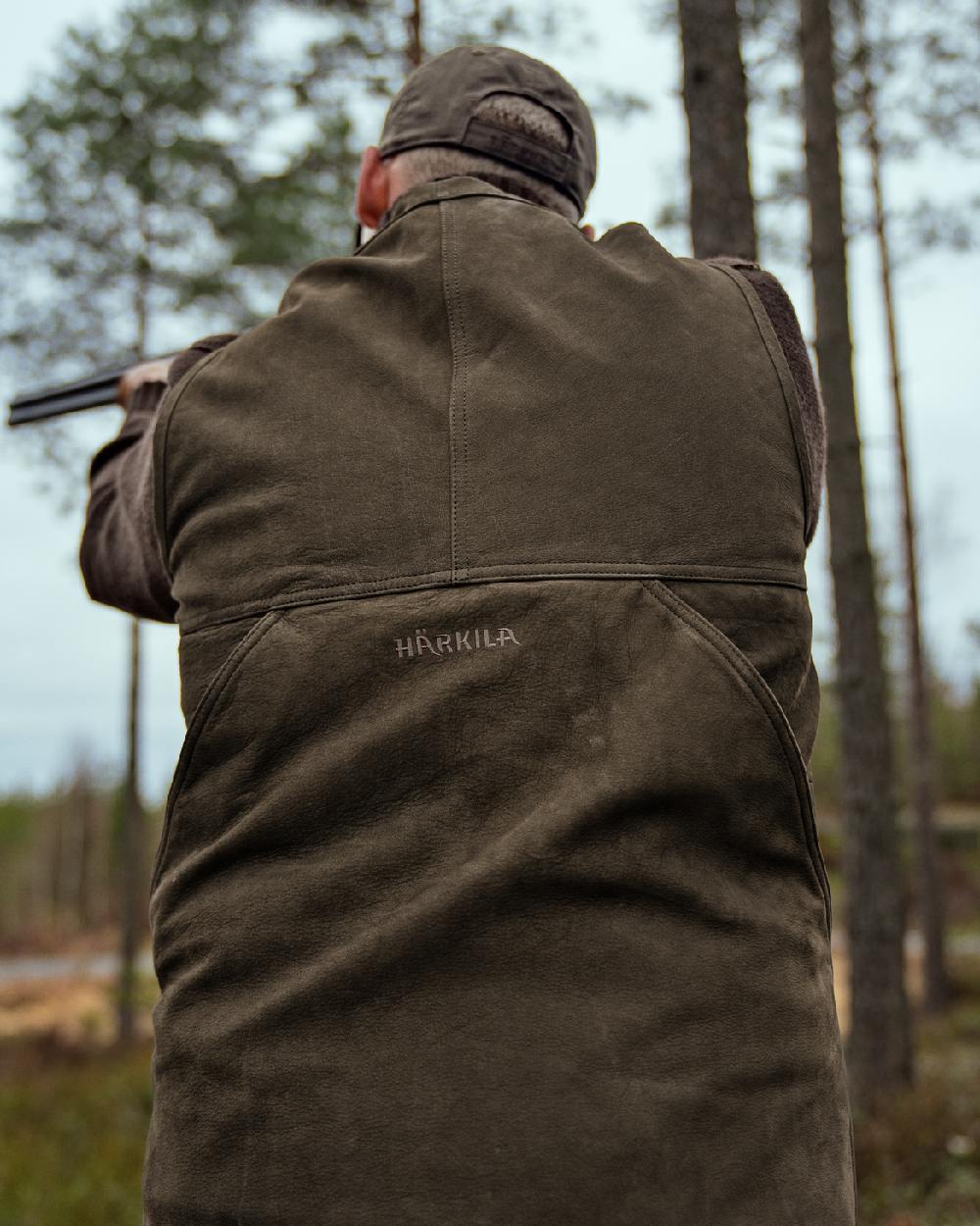 Willow Green Coloured Harkila Pro Hunter Leather Waistcoat on forest background #colour_willow-green