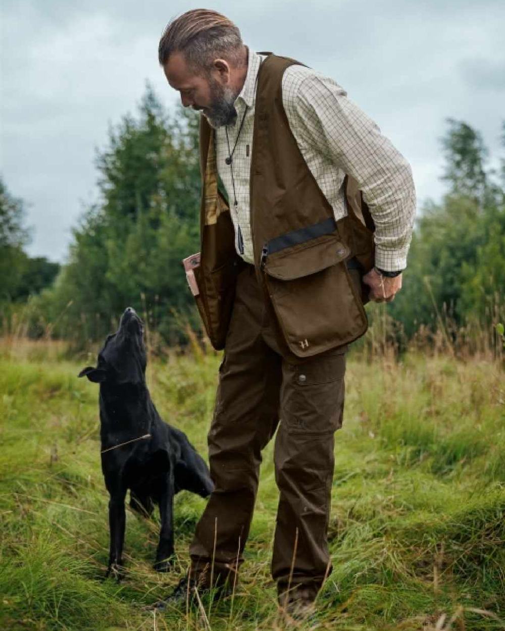 Warm Olive Coloured Harkila Retrieve Dummy Waistcoat on outdoor background #colour_warm-olive