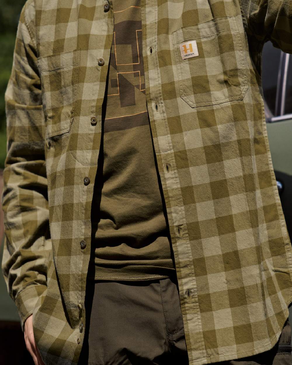 Dark Olive Check Coloured Harkila Scandinavian Long Sleeve Shirt on blurry background #colour_dark-olive-check