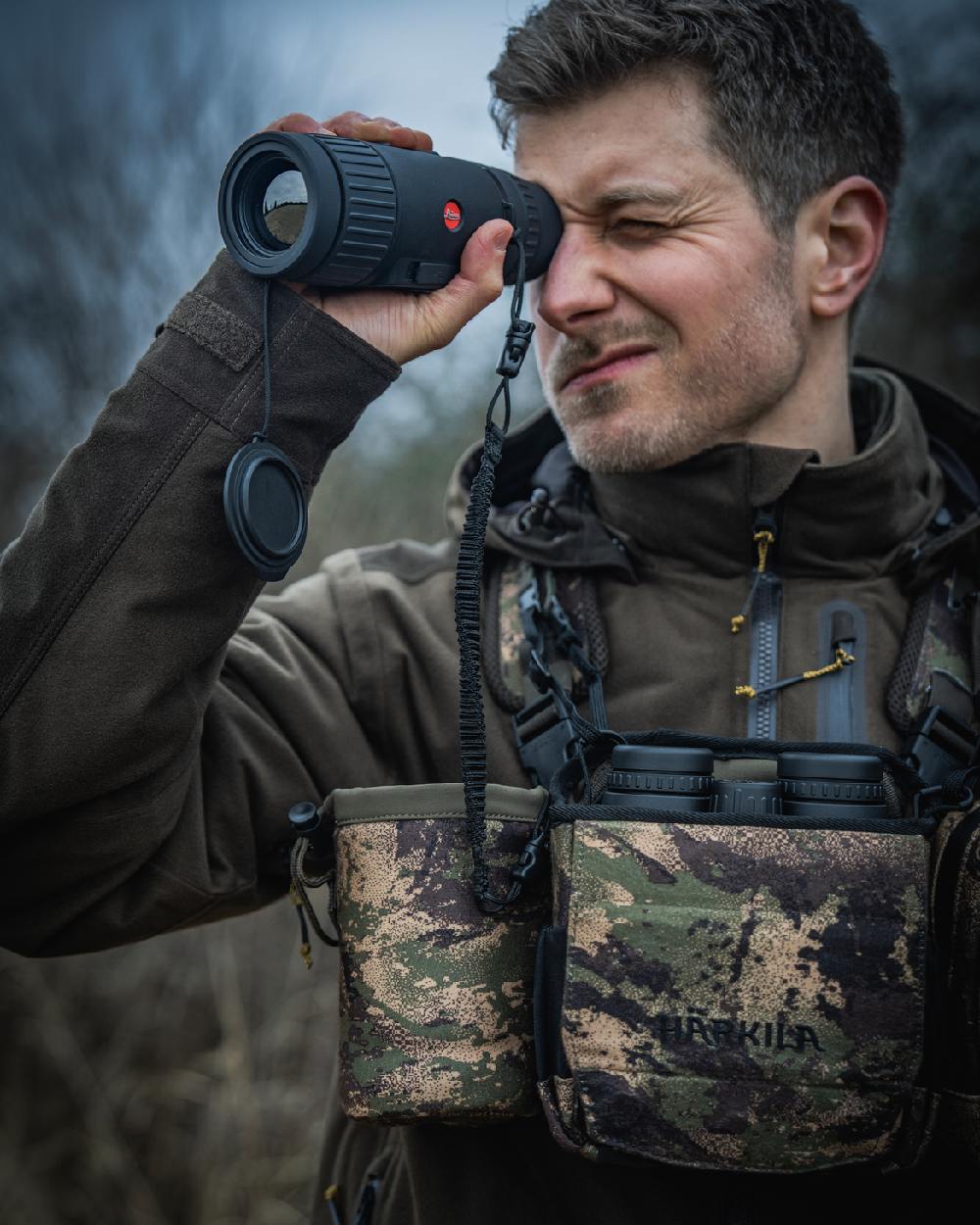 AXIS MSPForest Coloured Harkila Thermal Camo Spotter Pouch on blurry background #colour_axis-mspforest