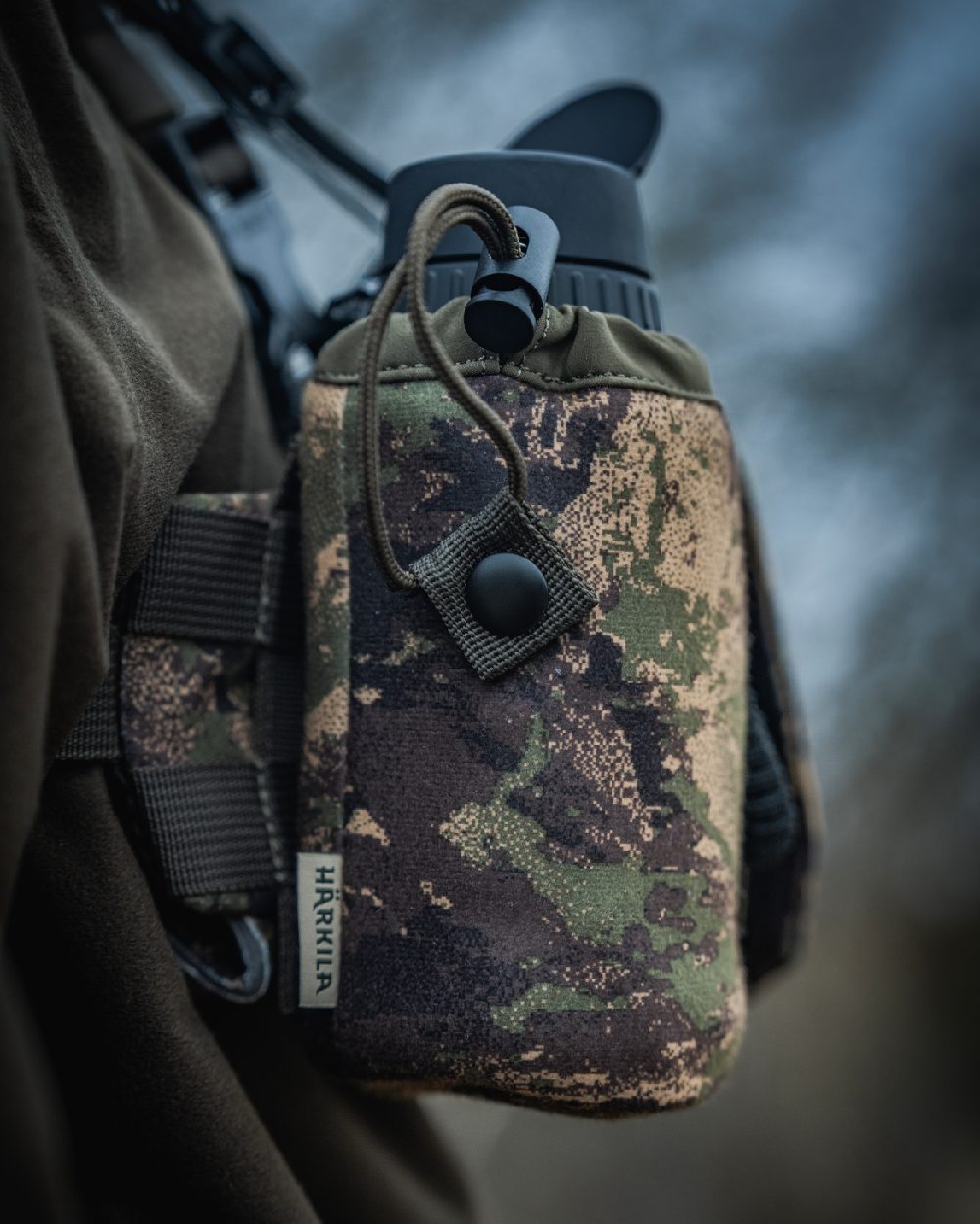 AXIS MSPForest Coloured Harkila Thermal Camo Spotter Pouch on blurry background #colour_axis-mspforest