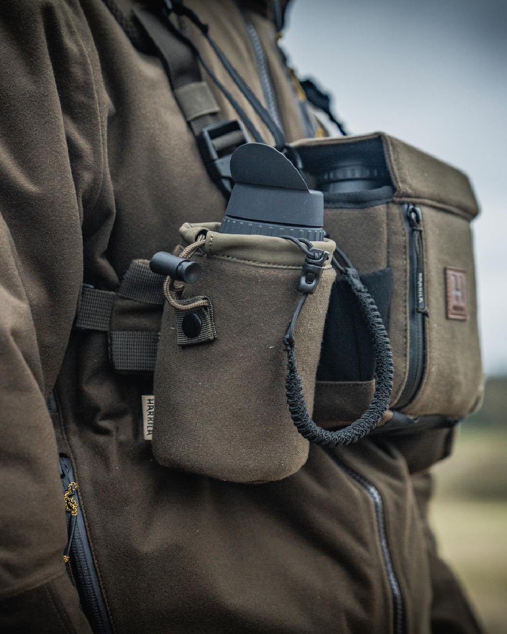 Dark Willow Green Coloured Harkila Thermal Spotter Pouch on blurry background #colour_dark-willow-green