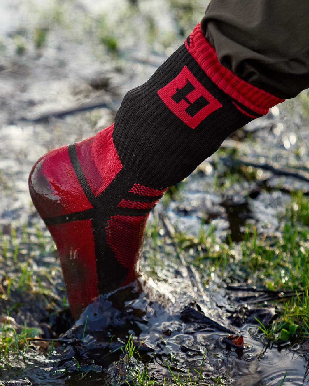 Red Black Coloured Harkila Waterproof Socks on outdoor background #colour_red-black