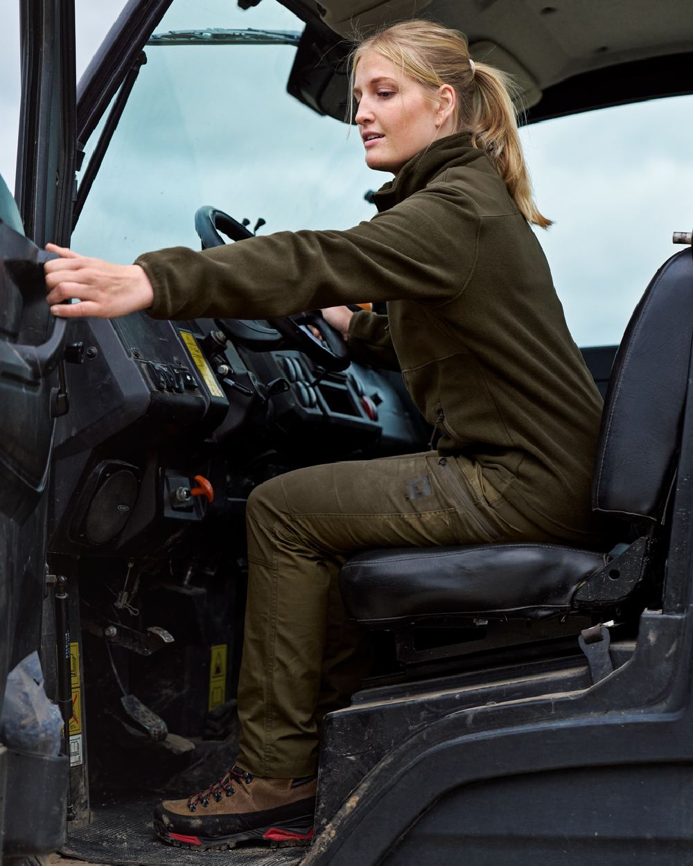 Dark Olive Willow Green Coloured Harkila Womens Fjell Trousers on tractor background #colour_dark-olive-willow-green