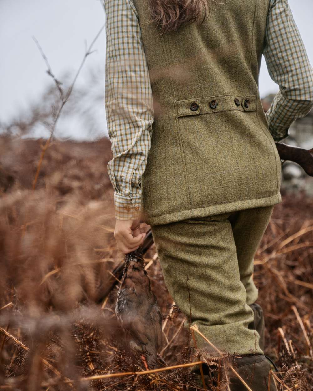 Olive Coloured Harkila Womens Jura Waistcoat on forest background #colour_olive