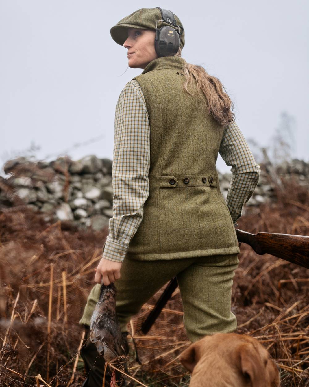 Olive Coloured Harkila Womens Jura Waistcoat on forest background #colour_olive