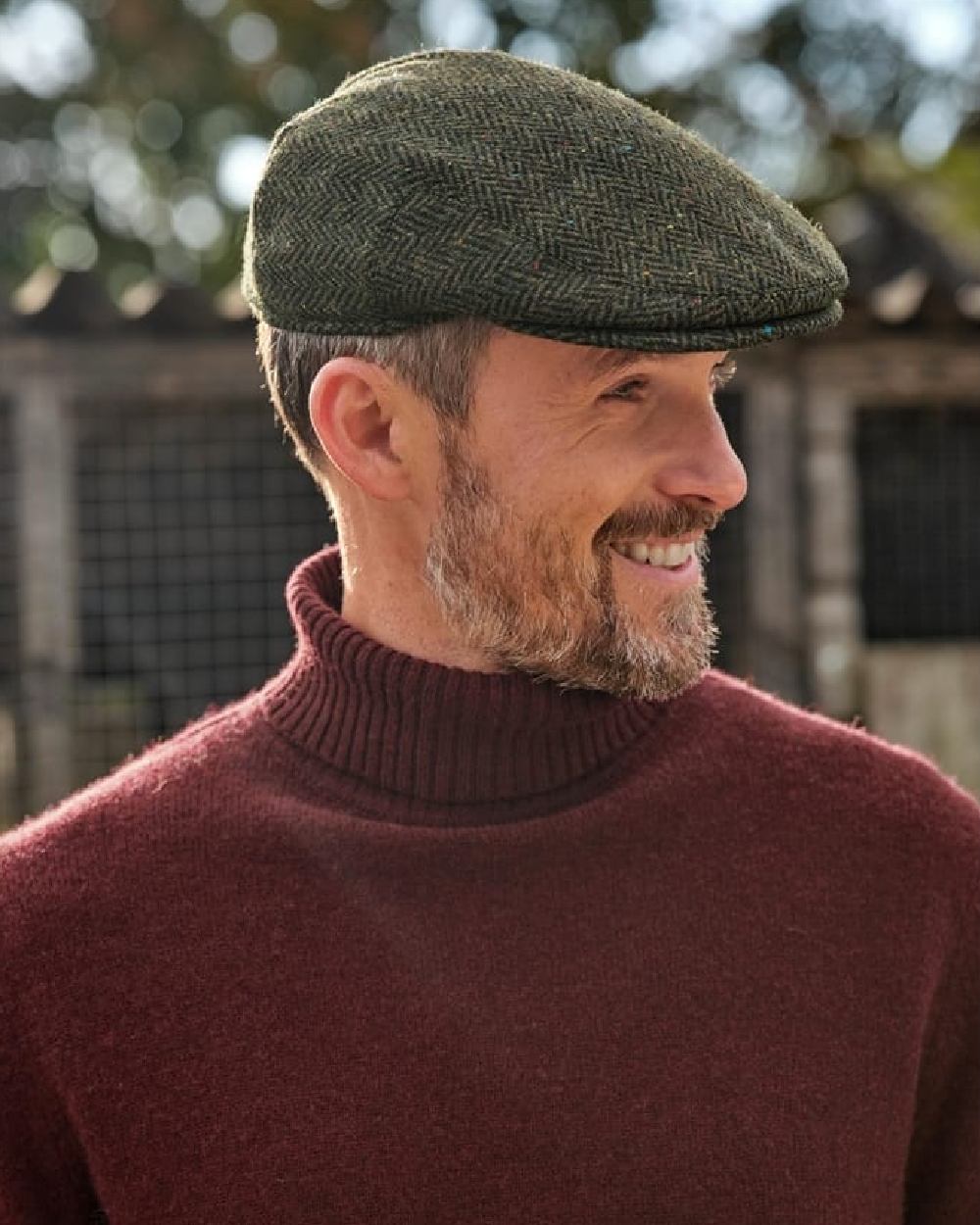 Green Coloured Hoggs of Fife Herringbone Waterproof Tweed Flat Cap on blurry background #colour_green