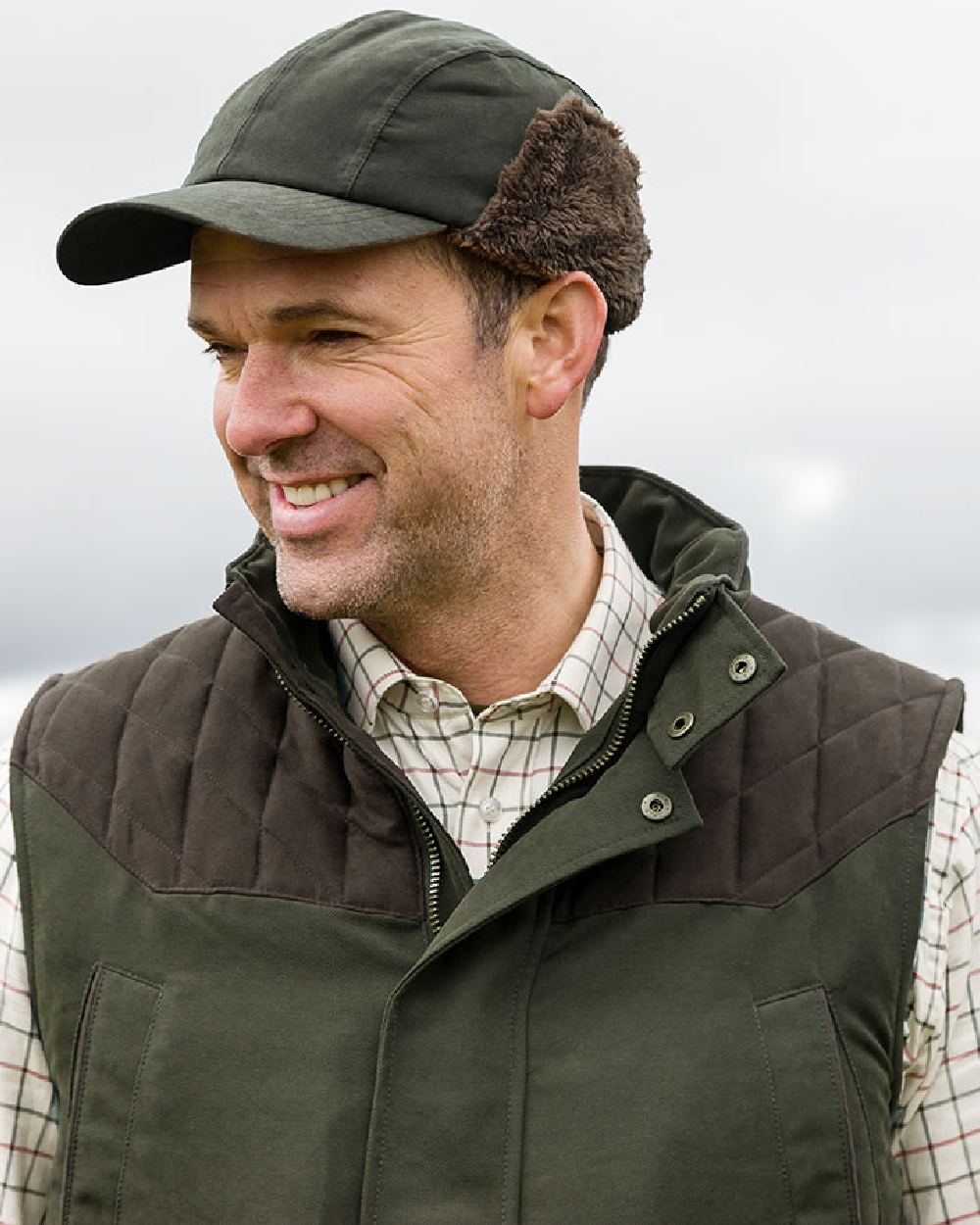 Olive Green Coloured Hoggs of Fife Kincraig Waterproof Hunting Cap on blurry background #colour_olive-green
