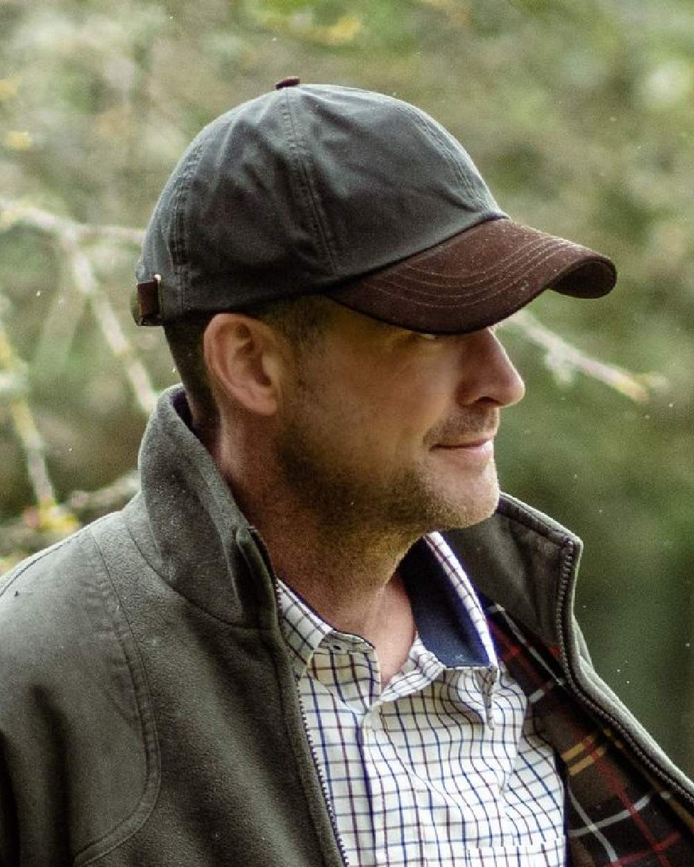 Olive Coloured Hoggs of Fife Leather Peak Waxed Baseball Cap on blurry background #colour_olive
