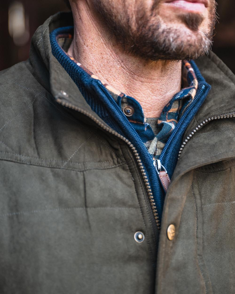 Loden coloured Hoggs of Fife Mens Glenbervie Quilted Gilet on blurry background #colour_loden