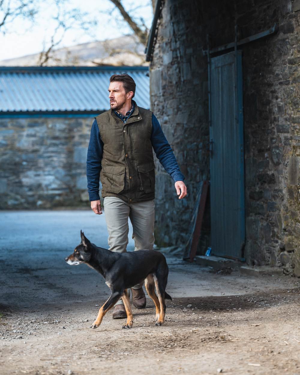Loden coloured Hoggs of Fife Mens Glenbervie Quilted Gilet on house background #colour_loden